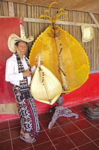 Jeremias in the traditional outfit with an acoustic sasandu and a giant replica