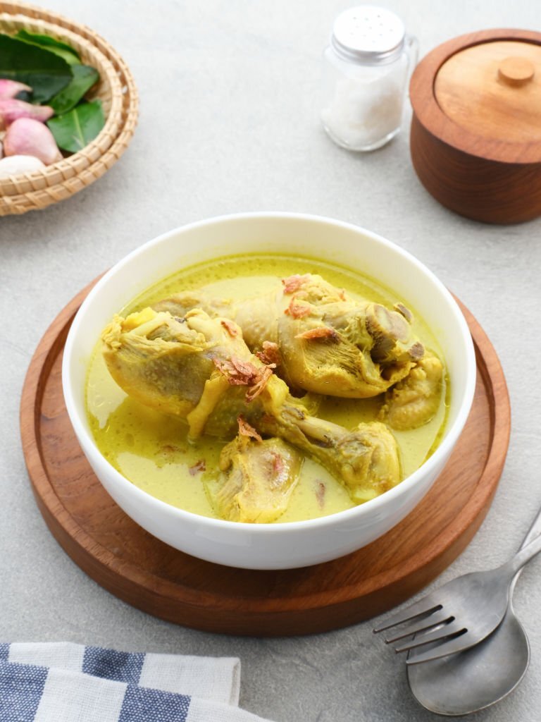 Opor Ayam, Indonesian traditional food in white bowl on grey background. Opor made from chicken cooked with coconut milk and spices. Its served to celebrate Eid Adha and Eid Fitr.