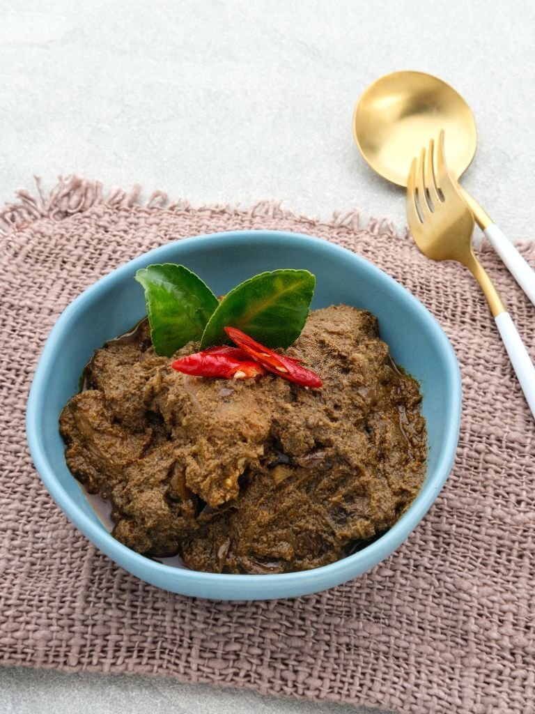 Rendang, Rendang Daging Sapi, Beef stew traditional food from Padang, Indonesia. The dish is arranged among the spices and herbs used in the original recipe like chili, lemongrass, onion, coconut milk
