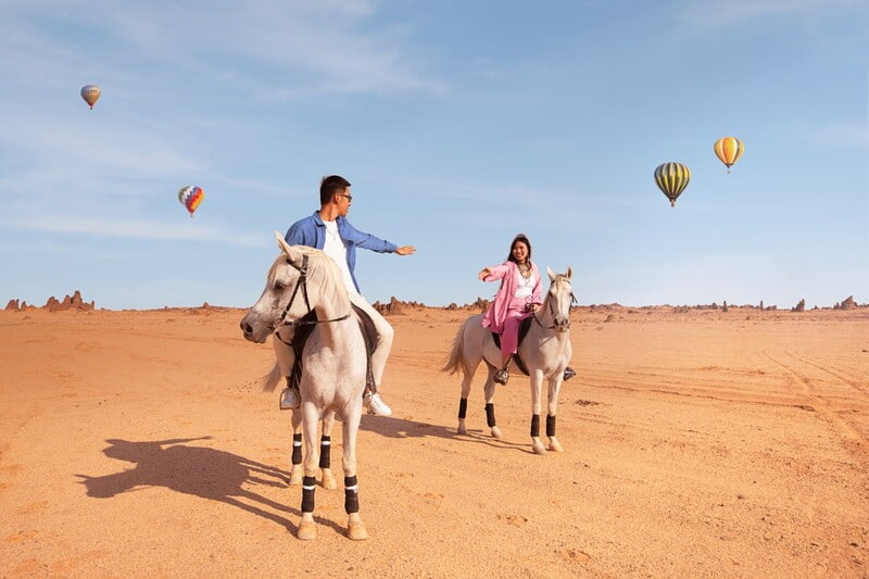 A couple horseback riding in the desert of Al-Ula