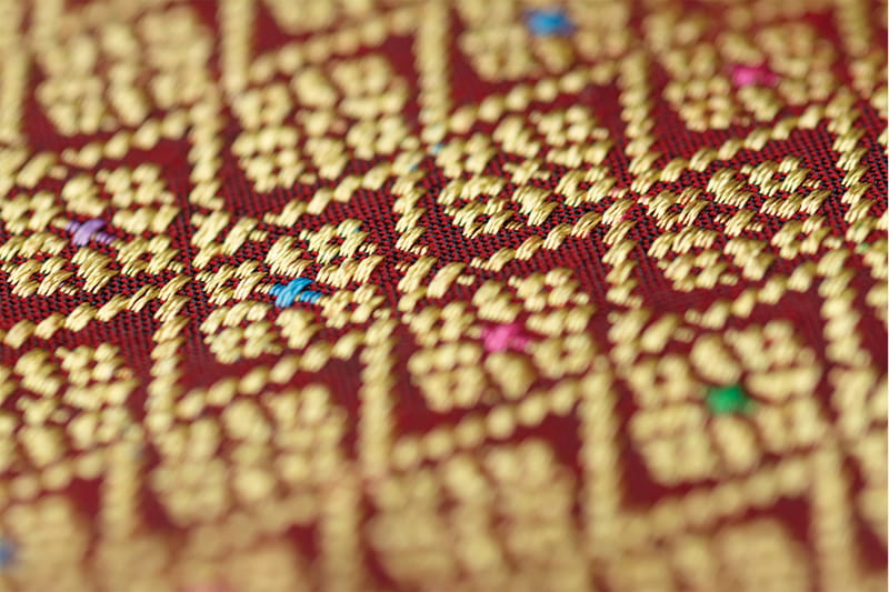 The intricate gold-thread geometric patterns of traditional Songket weaving